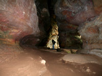 man in cave between cave rocks walking